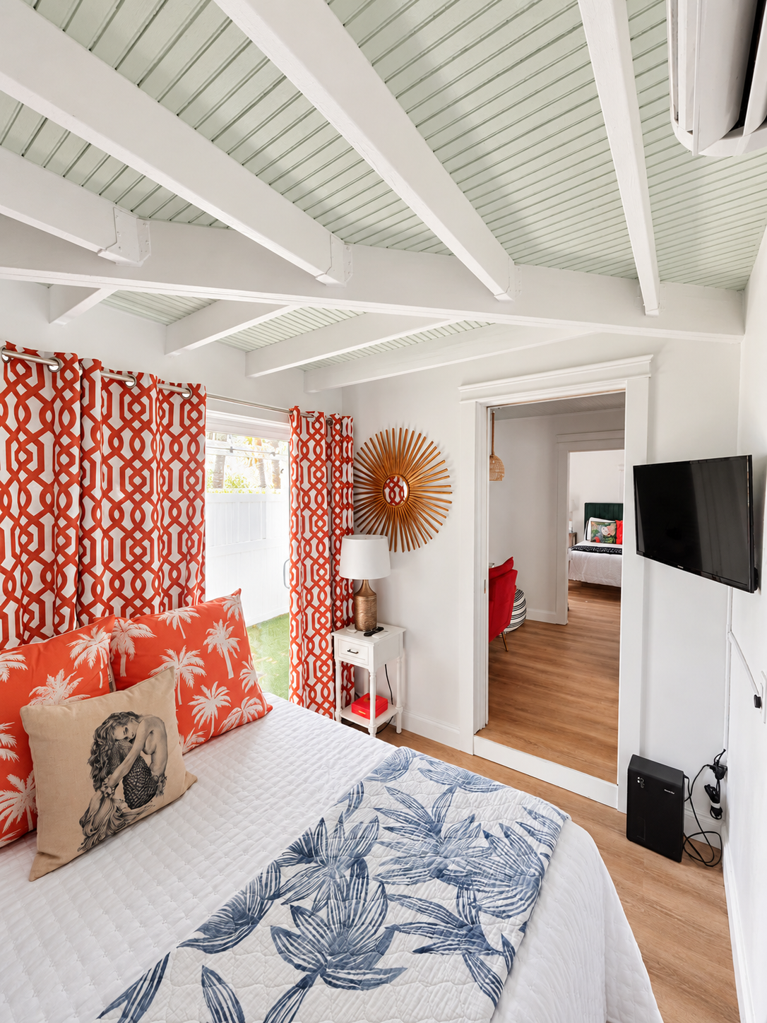 Second bedroom with coral curtains and palm pillows